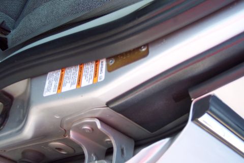 2001 Ford Crown Victoria - A close-up view of the driver's side door jamb of a vehicle, showing an airbag warning sticker and a small metal plate with stamped informa…