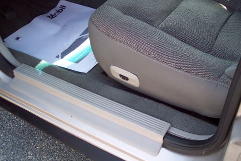 2001 Ford Crown Victoria - Interior view of a car's passenger side door sill and front seat. A Mobil service mat is visible on the floor mat.
