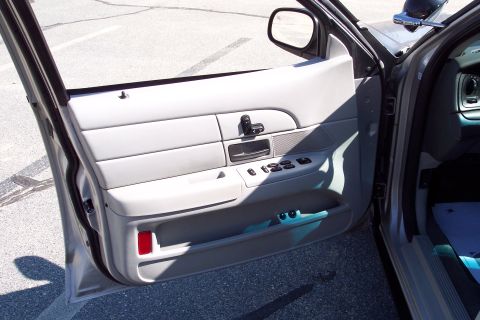 2001 Ford Crown Victoria - The interior of a car door is shown, focusing on the door panel with various controls and a storage compartment. The door is open, revealin…