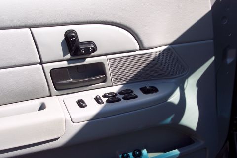 2001 Ford Crown Victoria - The interior door panel of a car shows power window controls, a door handle, and seat adjustment buttons. The controls are black plastic ag…