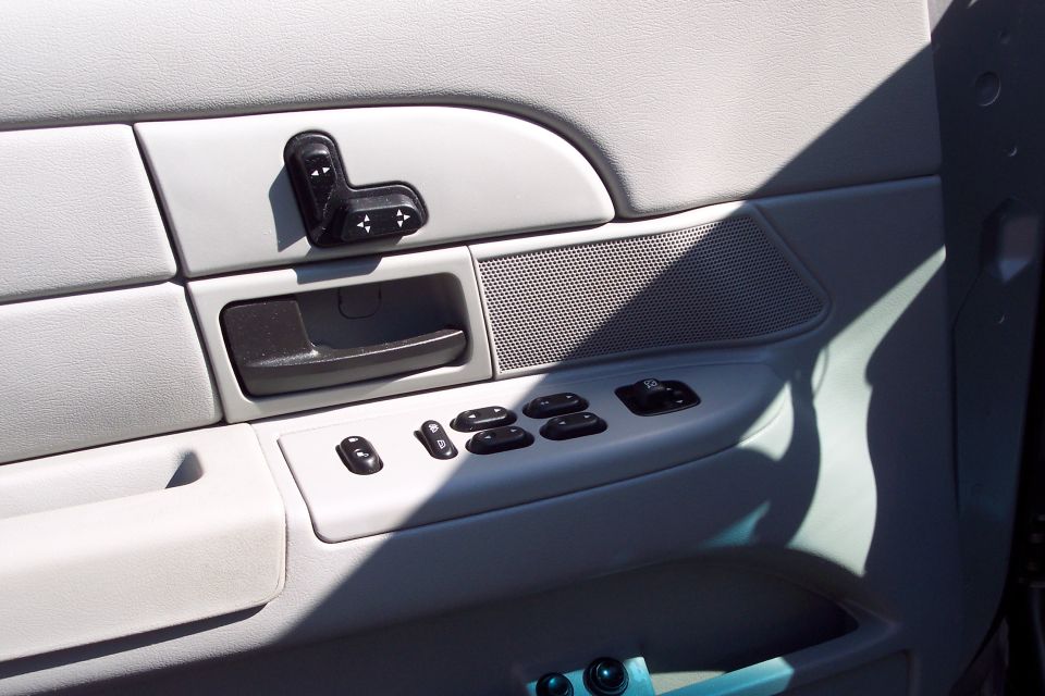 Car door interior panel with power window controls, door handle, and seat buttons.