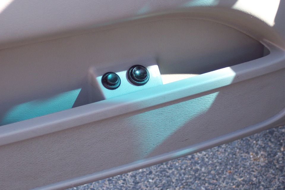 Close-up of two black buttons on a car door panel.
