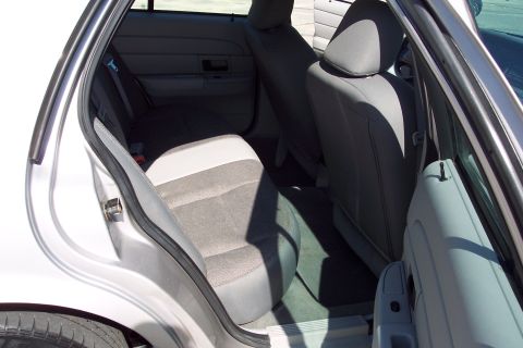 2001 Ford Crown Victoria - The interior of the rear passenger side of a silver sedan is shown, featuring gray fabric seats and door panels. A portion of the rear tire…