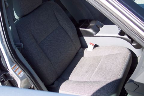 2001 Ford Crown Victoria - The interior of a vehicle shows the front passenger seat and part of the center console. A seatbelt buckle is visible on the right side of…