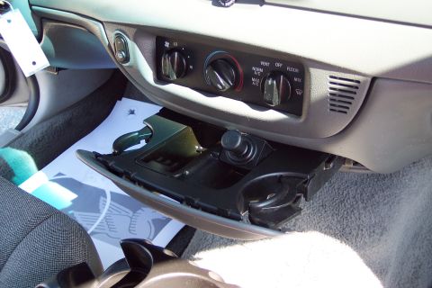 2001 Ford Crown Victoria - Interior view of the center console of a 2001 Ford Crown Victoria, showing the climate controls and an open storage compartment with a 12v…