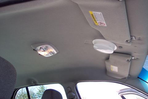 2001 Ford Crown Victoria - Interior view of the headliner in a vehicle, showing two dome lights and a sun visor with a warning sticker.