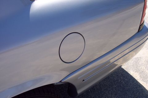 2001 Ford Crown Victoria - Close-up view of the rear quarter panel of a silver sedan, showing the fuel filler door and part of the rear bumper. The vehicle is parked…