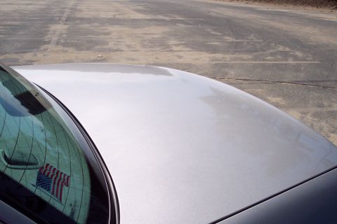 2001 Ford Crown Victoria - Close-up of a silver car's hood and windshield, showing a portion of the vehicle's exterior.