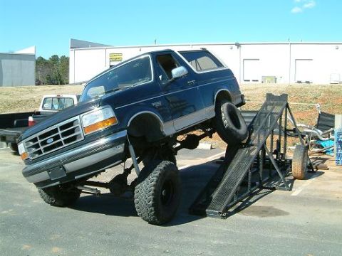1993 Ford Bronco - A modified 1993 Ford Bronco is positioned on a ramp, its lifted suspension and off-road tires.