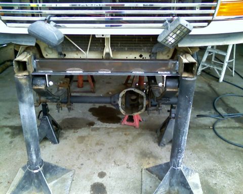 1996 Ford Bronco - Front axle assembly of a 1996 Ford Bronco undergoing modifications, supported by jack stands.