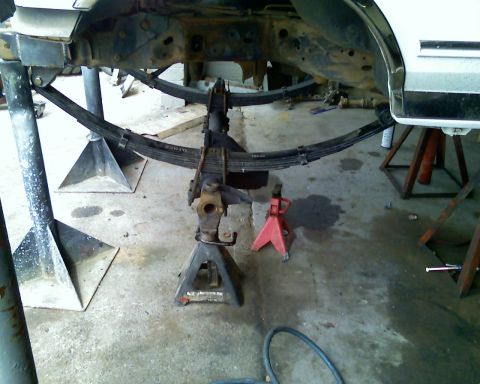 1996 Ford Bronco - Close-up view of a vehicle's leaf spring suspension system supported by jack stands.