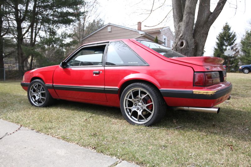 red fox body Mustang parked on grass, aftermarket wheels, spoiler