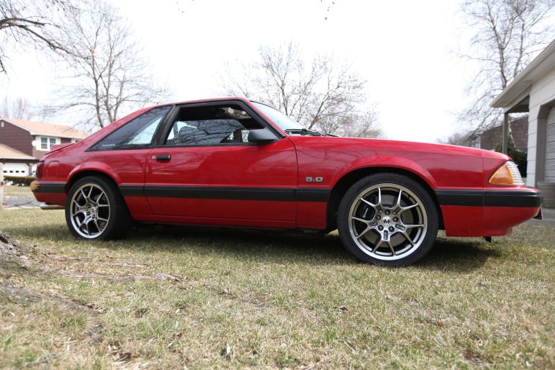 Red 1990 Ford Mustang coupe with aftermarket wheels and 5.0 badge