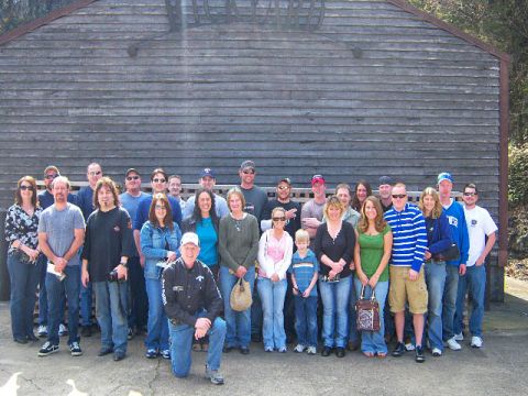 2007 Ford Mustang - A group of people gathered outdoors in front of a large wooden structure.