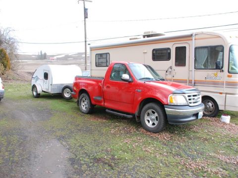 1988 Ford Bronco - A red Ford F-150 pickup truck from the late 1990s is parked next to an RV, with a teardrop trailer attached.