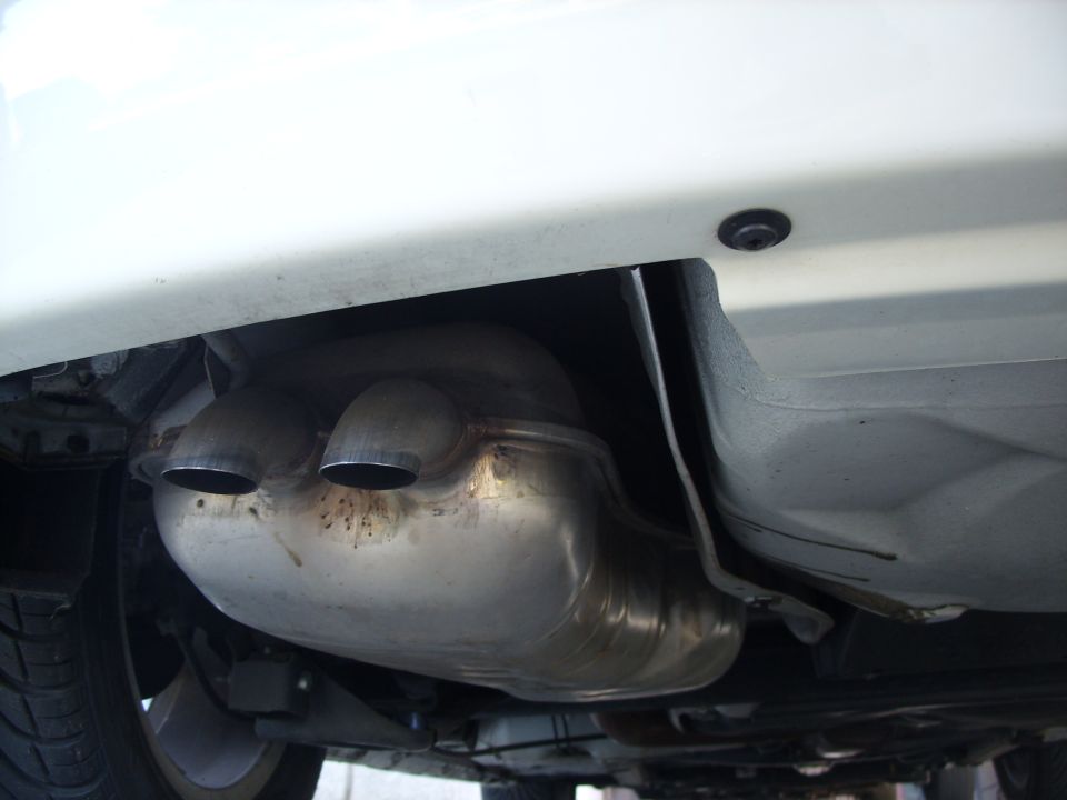 Stainless dual center-exit exhaust tips under the rear bumper of a white car