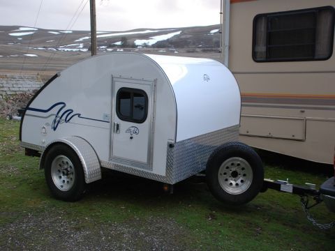 1988 Ford Bronco - A white teardrop trailer is parked on a grassy area next to a larger RV.