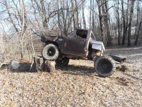 1980 Dodge Magnum - A modified pickup truck is shown with one wheel elevated on a tree stump in a wooded area.