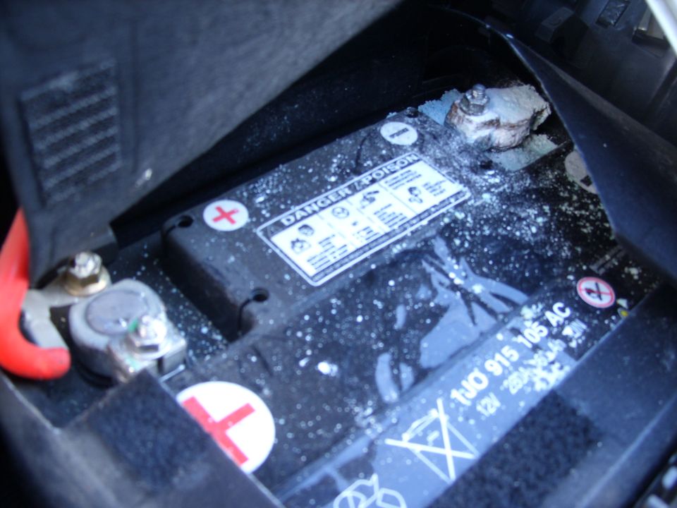 Corroded battery terminal on a 12V VW battery (1J0 915 105 AC) with white corrosion residue