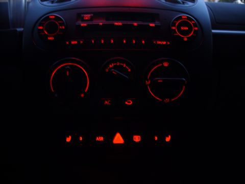 2003 Volkswagen Beetle - The interior dashboard of a vehicle glows with red illumination on its controls and buttons.