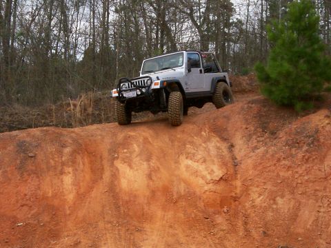 1993 Ford Bronco - A Jeep Wrangler TJ navigates an off-road trail, its tires gripping the loose dirt.