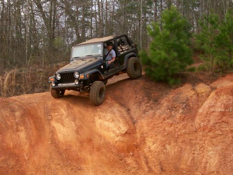 1993 Ford Bronco - A black Jeep Wrangler TJ navigates a steep, sandy incline during an off-road excursion.