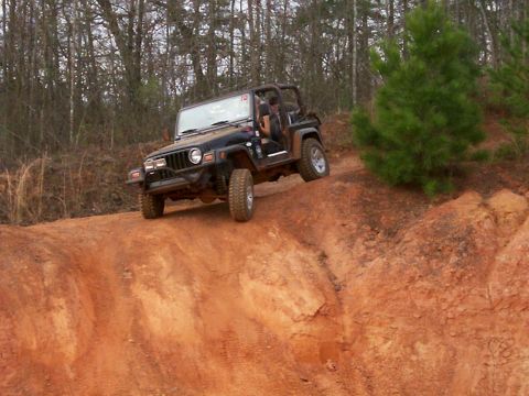 1993 Ford Bronco - A black Jeep Wrangler TJ navigates a steep, sandy incline on an off-road trail.