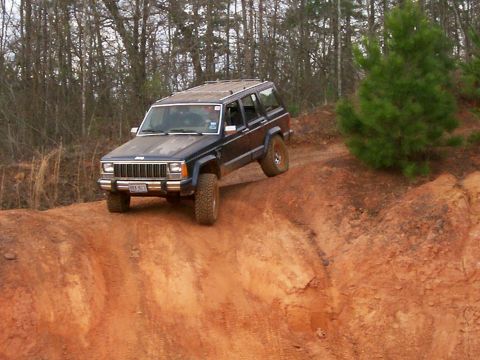 1993 Ford Bronco - Jeep Cherokee XJ navigates a steep dirt embankment during an off-road excursion.