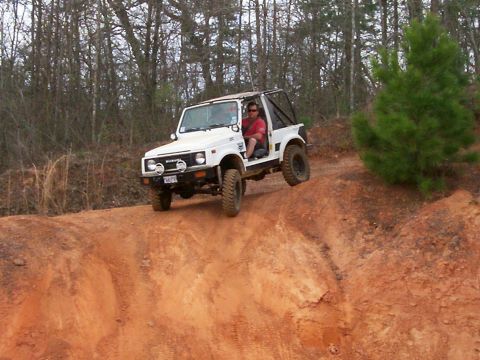 1993 Ford Bronco - A Suzuki Samurai navigates a steep, sandy incline on an off-road trail.