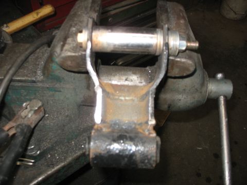 1995 Ford C-350 (Centurion Conversions) - A close-up view of a vehicle suspension component secured in a metal vise, ready for work.