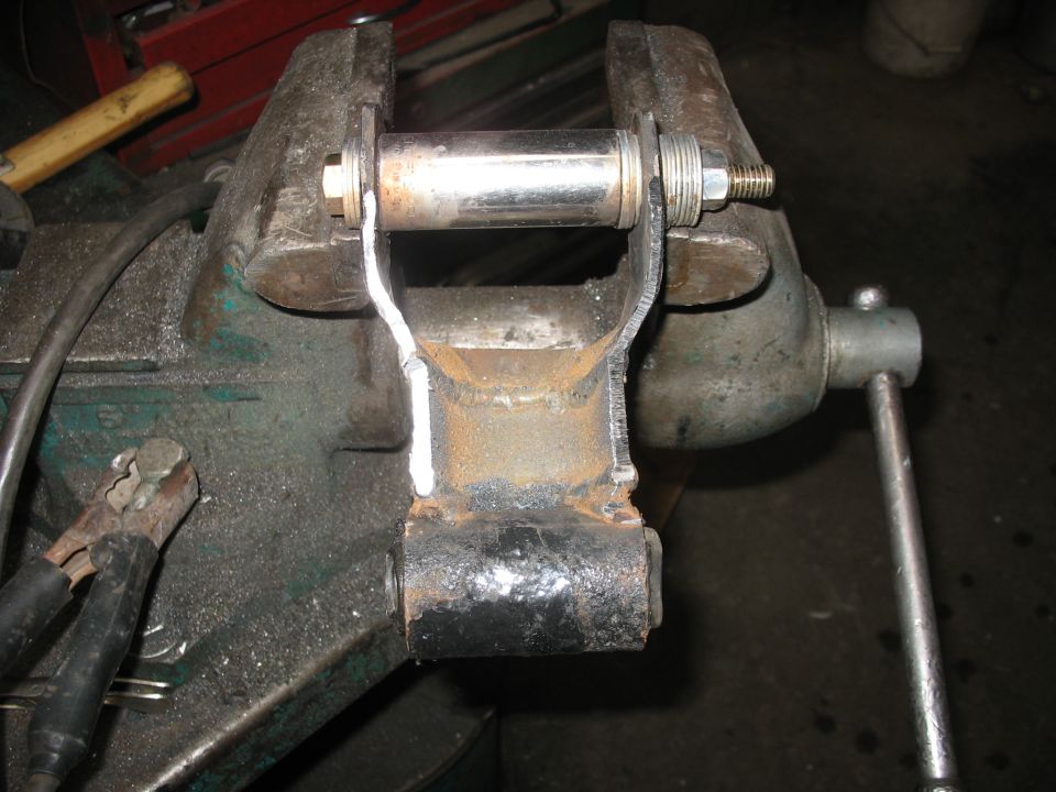 Leaf spring shackle held in a vise, with a bolt and nut assembly