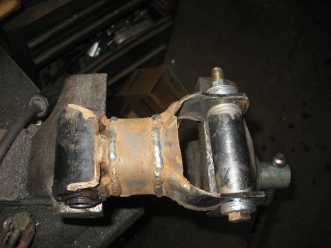1995 Ford C-350 (Centurion Conversions) - A rusty suspension part is secured in a vise, showing signs of wear and repair.