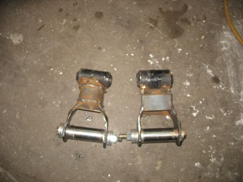1995 Ford C-350 (Centurion Conversions) - Two custom leaf spring shackles are shown lying on a concrete floor, possibly for a Ford C-350 conversion.