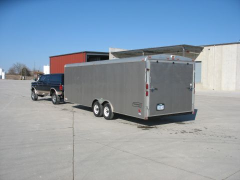 1995 Ford C-350 (Centurion Conversions) - A 1992 Ford pickup truck tows a large silver enclosed trailer on a paved lot under a clear blue sky.