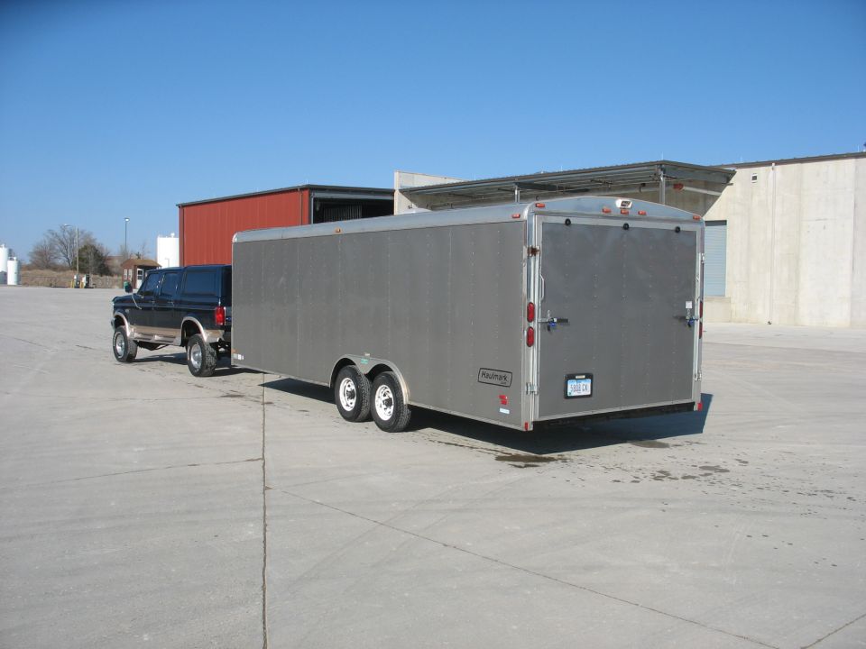 1992 Ford F-250/F-350 Super Duty pickup truck towing a silver enclosed trailer. The truck is dark blue with tan trim