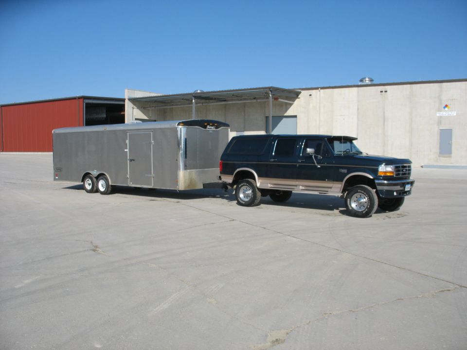 Dark blue 1995 Ford C-350 Centurion Conversions SUV towing a silver trailer