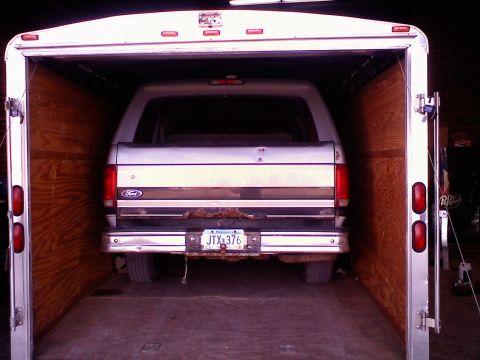 1995 Ford C-350 (Centurion Conversions) - Silver Ford F-Series truck with a rusty tailgate is parked inside a trailer.
