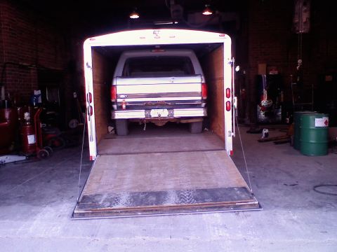 1995 Ford C-350 (Centurion Conversions) - A white Ford Bronco is parked inside a trailer, viewed from the rear.
