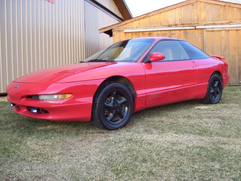 1996 Ford Probe - A red 1996 Ford Probe GT is parked outside a building with wooden and metal siding.