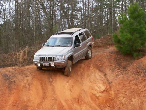 1993 Ford Bronco - A silver Jeep Grand Cherokee navigates a steep dirt incline during an off-road excursion.