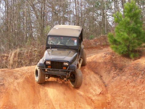 1993 Ford Bronco - This Jeep Wrangler is navigating a steep, sandy incline on an off-road trail.