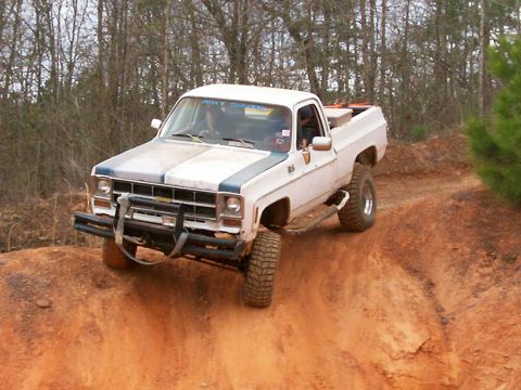 1993 Ford Bronco - A lifted pickup truck navigates a dirt trail during an off-road event.
