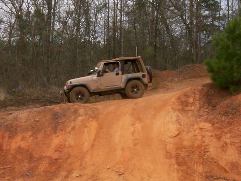 1993 Ford Bronco - A Jeep Wrangler TJ navigates an off-road trail with a driver visible inside.
