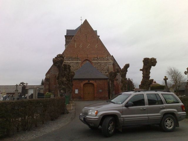 Silver Jeep Grand Cherokee parked in front of a brick church with a cemetery
