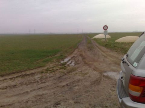 1991 Ford LTD Crown Victoria - Silver SUV on a muddy road in a rural landscape.