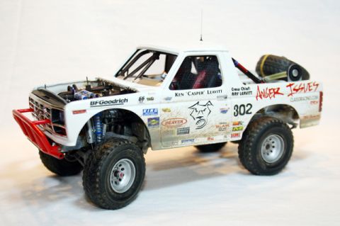 1986 Ford Bronco - White off-road truck with racing decals and an open hood, a prominent red bull bar.