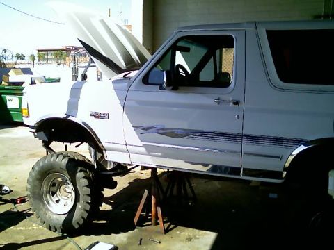 1996 Ford Bronco - This 1996 Ford Bronco is lifted on jack stands with its hood open, revealing modifications and large off-road tires.