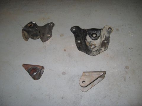 1991 Ford Bronco - Four assorted metal brackets laid out on a concrete surface.
