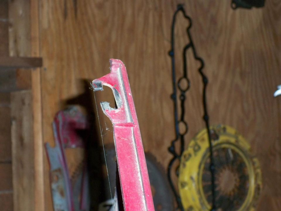 Red plastic trim piece with visible damage and a black gasket hanging behind it
