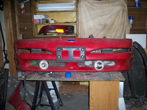 1995 Ford Probe - Front bumper assembly for a 1995 Ford Probe, integrated fog lights and the iconic Ford blue oval emblem.